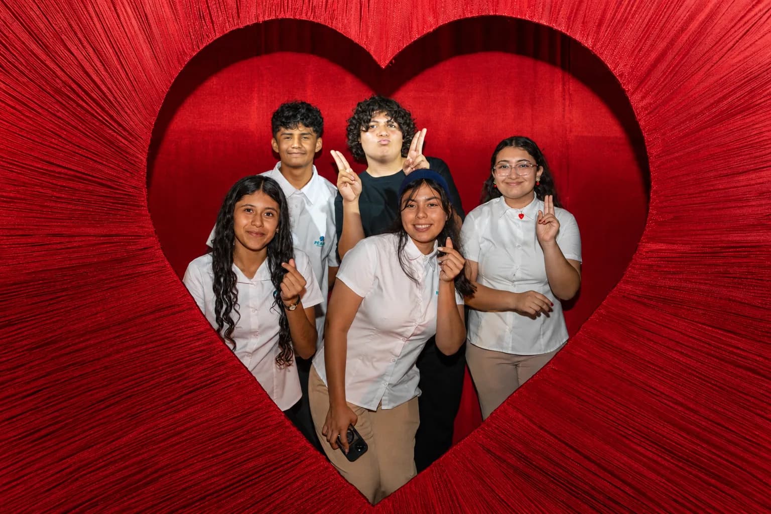 Beneficiarios de PEACE Punta de Mita sonriendo juntos dentro de un corazón rojo gigante