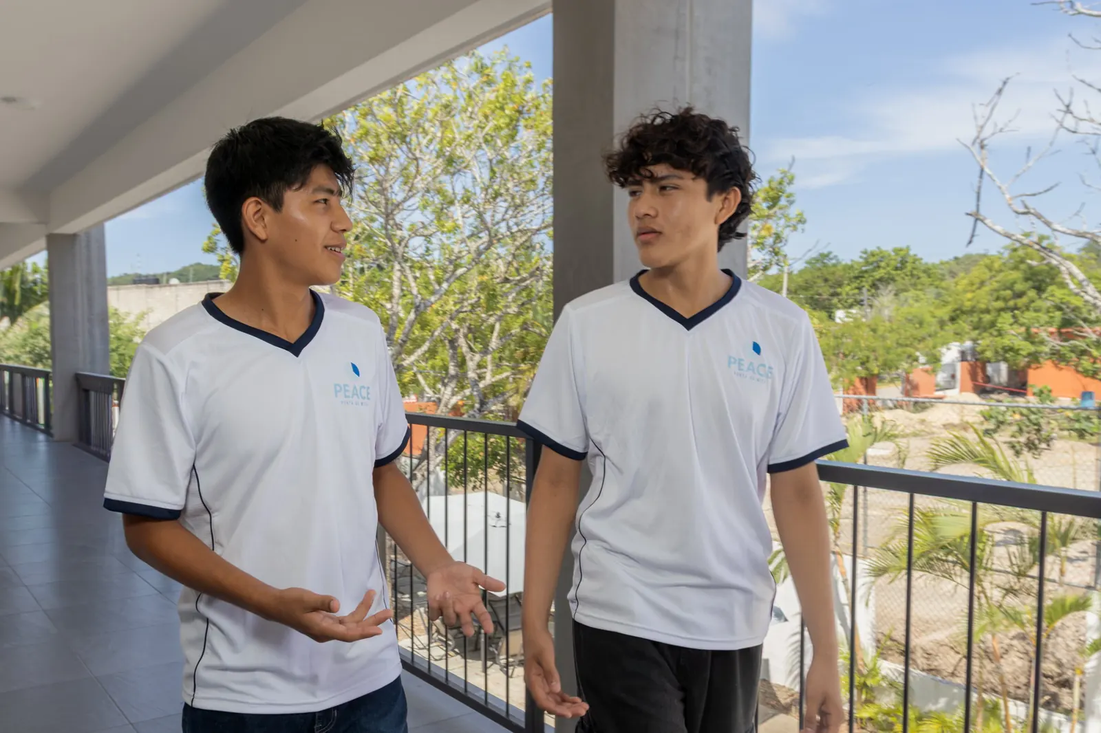Dos estudiantes de PEACE Punta de Mita platicando mientras caminan por una terraza de Campus de Mita